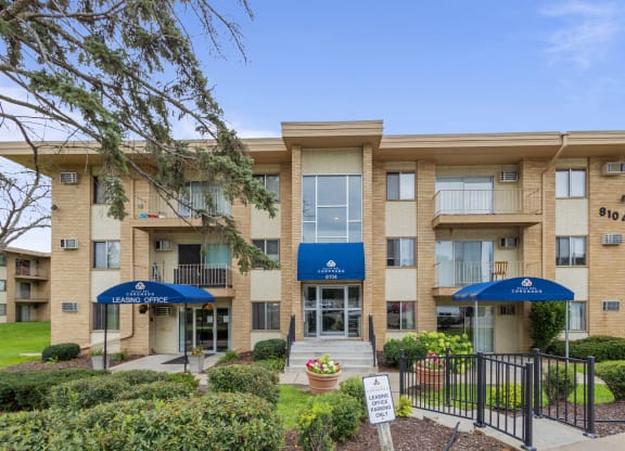an apartment building with umbrellas and a sign in front