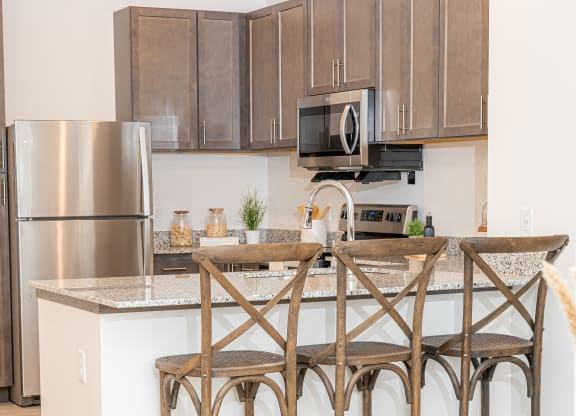 a kitchen with an island with three bar stools and a stainless steel refrigerator