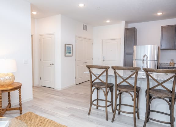 a living room with a kitchen and a bar with three stools