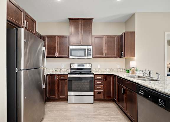 A kitchen with brown cabinets and a stainless steel refrigerator at The Winslow 62+ Apartments, West St Paul, 55118