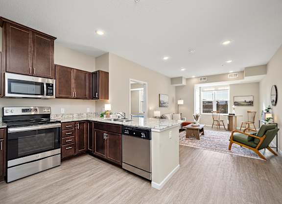 A kitchen with brown cabinets and stainless steel appliances at The Winslow 62+ Apartments, Minnesota, 55118