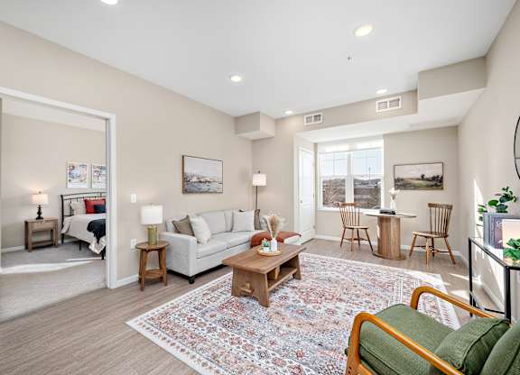A living room with a white couch, a coffee table, and a rug at The Winslow 62+ Apartments, West St Paul, MN