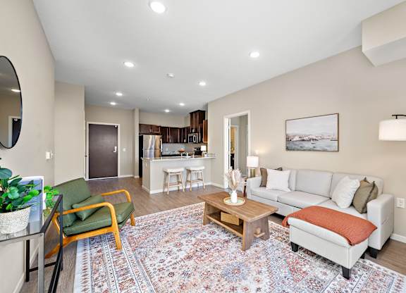 A living room with a rug on the floor and a couch with pillows at The Winslow 62+ Apartments, West St Paul, 55118