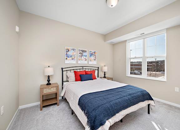 A bedroom with a bed, nightstand, and pictures on the wall at The Winslow 62+ Apartments, West St Paul, MN, 55118