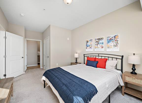 A bedroom with a bed, nightstand, and a painting on the wall at The Winslow 62+ Apartments, West St Paul, MN