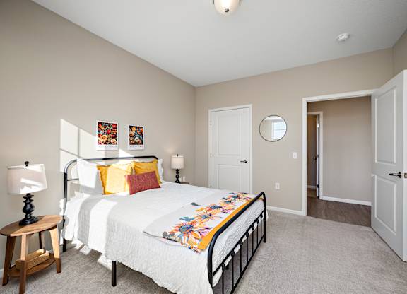 A bedroom with a bed, a nightstand, and a mirror at The Winslow 62+ Apartments, West St Paul, 55118