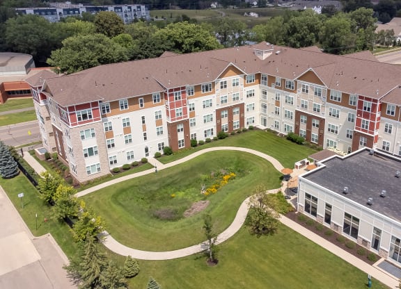 an aerial view of an apartment building with a green lawn and sidewalk at The Winslow 62+ Apartments, Minnesota