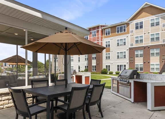 a patio with an umbrella and a table with chairs and a grill at The Winslow 62+ Apartments, Minnesota