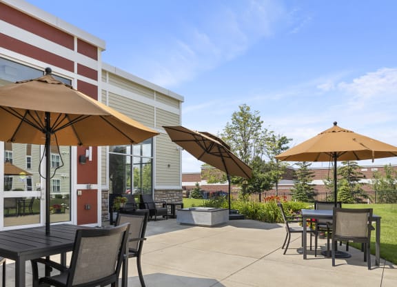 a patio with tables and umbrellas in front of a building at The Winslow 62+ Apartments, West St Paul, MN, 55118