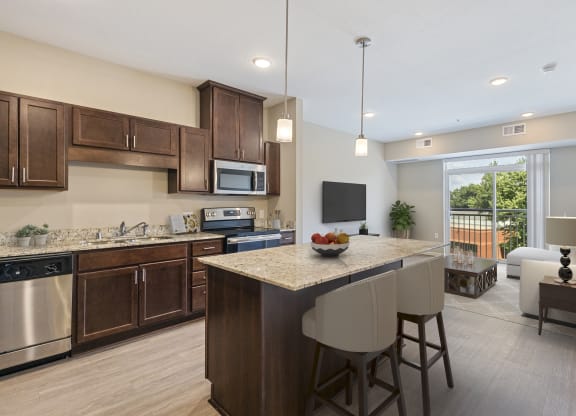 a kitchen and living room with a large island with a granite counter top at The Winslow 62+ Apartments, West St Paul, 55118