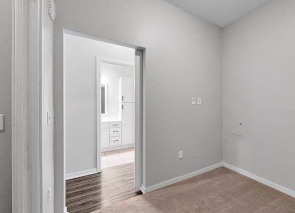 A room with white walls and a doorway leading to another room.