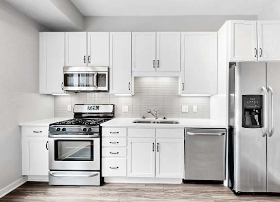 A modern kitchen with white cabinets and stainless steel appliances.