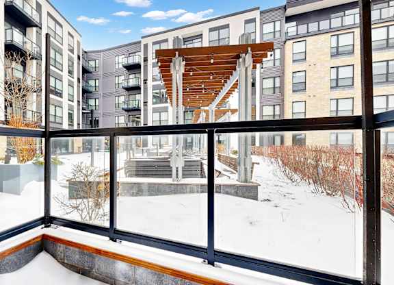 A balcony with a view of a snowy landscape and apartment buildings.