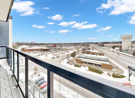 A balcony overlooks a busy highway and a parking lot.