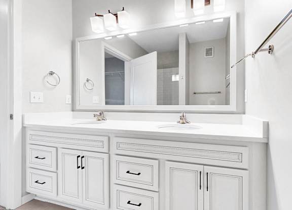 A white bathroom vanity with a mirror and lights above it.