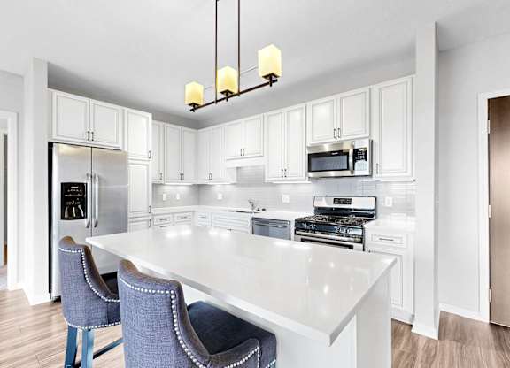 A kitchen with a white table and blue chairs.