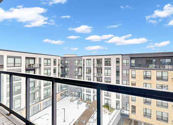A modern apartment complex with a glass balcony overlooking a snowy parking lot.
