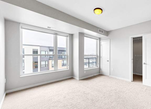 A spacious room with large windows and a carpeted floor.