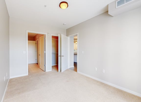 a bedroom with a carpeted floor and a door to a bathroom