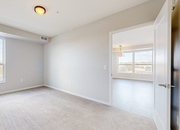 a bright bedroom with two windows and a door