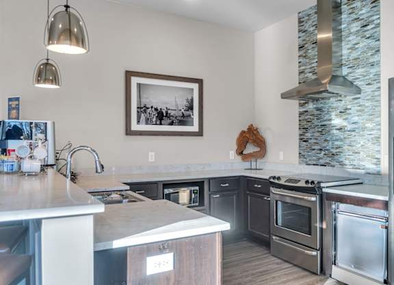 A woman is standing in a kitchen with stainless steel appliances.
