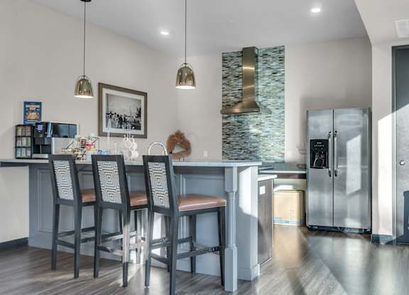 A kitchen with a bar area and a refrigerator with a glass door.