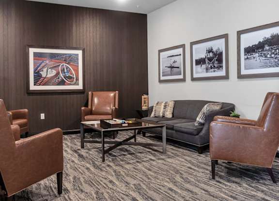 A living room with brown leather chairs and a grey couch.