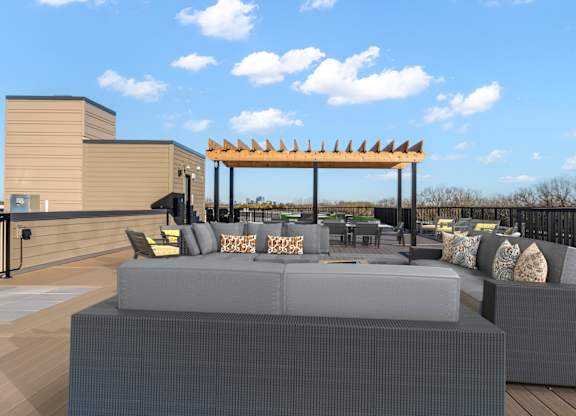 A modern outdoor seating area with grey couches and a wooden pergola.