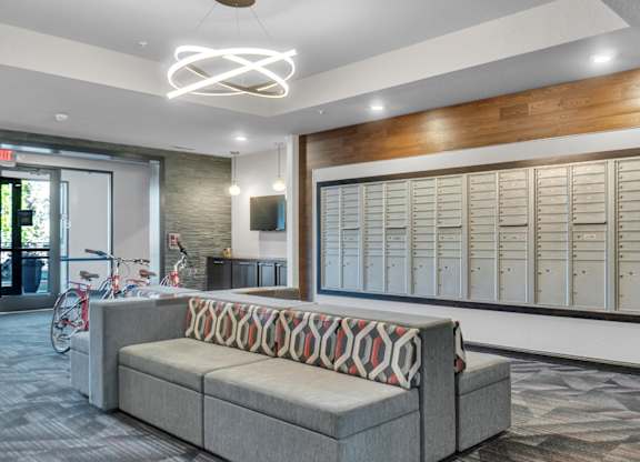 A modern office space with a grey sofa and a wooden accent wall.