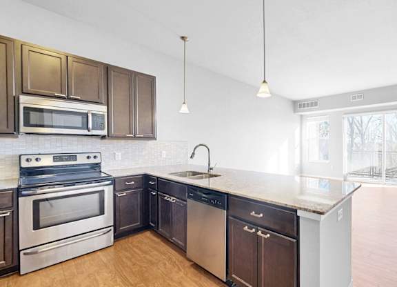 A kitchen with dark brown cabinets and stainless steel appliances.
