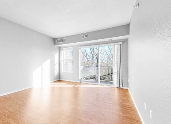 A room with wooden flooring and a sliding glass door leading outside.