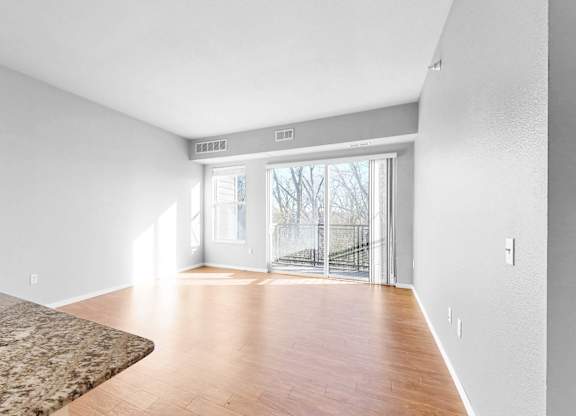 A room with a marble floor and wooden flooring leading to a glass door.
