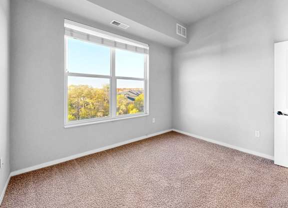 A room with a large window and a carpeted floor.