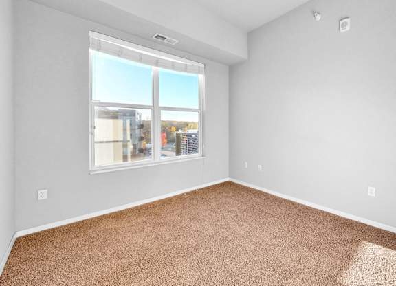 A room with a carpeted floor and a large window.