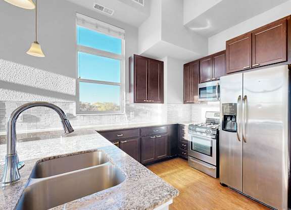 A modern kitchen with a stainless steel refrigerator and a marble countertop.