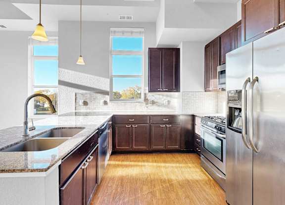 A modern kitchen with dark wood cabinets and stainless steel appliances.