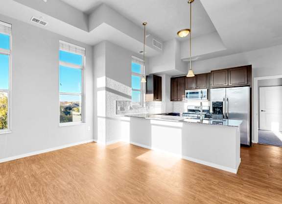 A spacious kitchen with a bar area and a view of trees outside the window.