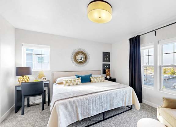 A bedroom with a bed, desk, and chairat Field and Grove Townhomes of Champlin, Champlin.