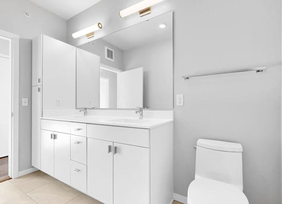 A white bathroom with a toilet, sink, and mirror.