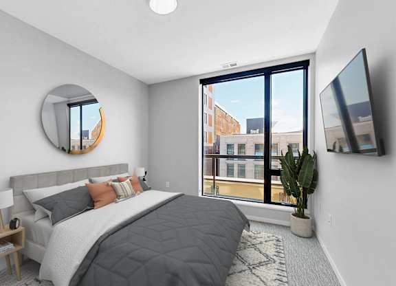 A bedroom with a large bed and a flat screen TV mounted on the wall.