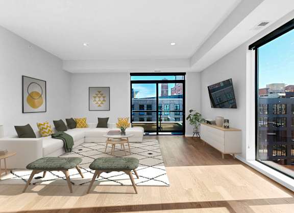 A living room with a white couch, a green chair, and a wooden floor.