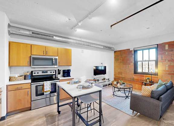 A kitchen with a table and chairs in front of a brick wall.
