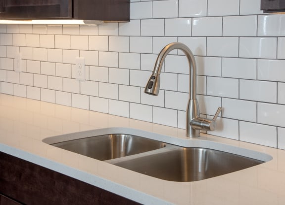 quartz countertops and tile backsplash and undercabinet lighting