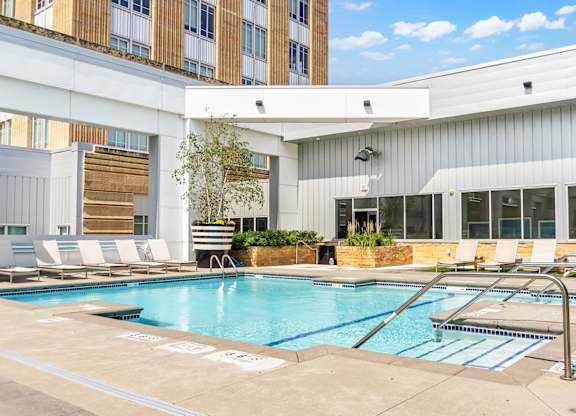 A swimming pool in a courtyard surrounded by chairs and plants.