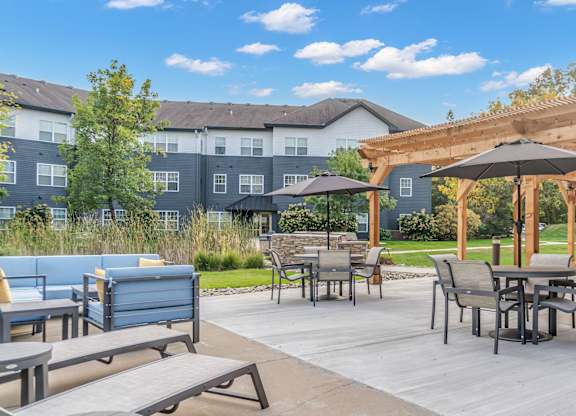 A patio with a table and chairs under a wooden pergola.