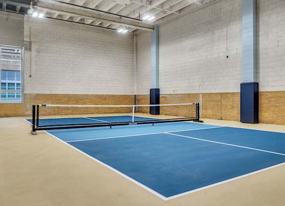A tennis court with a net and two blue posts.