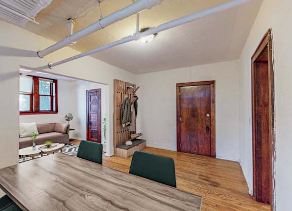 A room with a long wooden table and green chairs.