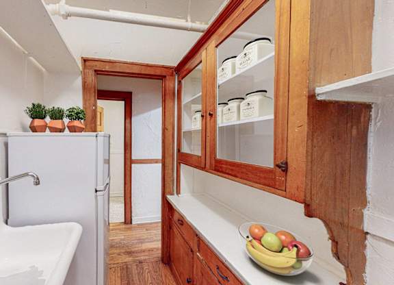 A kitchen with a white sink and wooden cabinets.