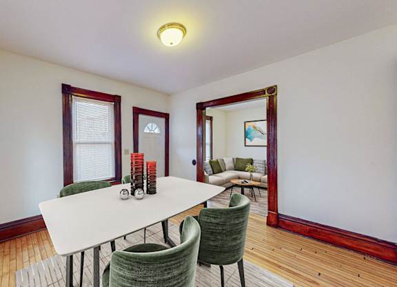 A dining room with a white table and green chairs.