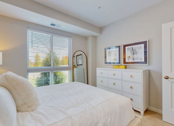 a white bedroom with a large bed and a window
